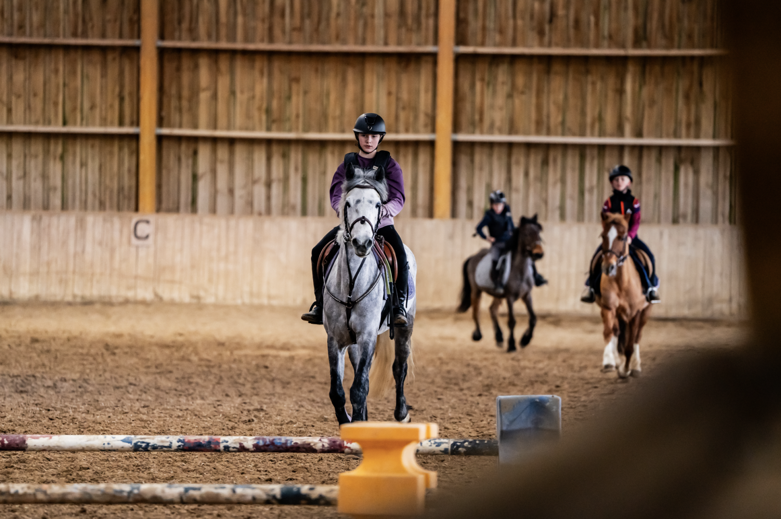 Un groupe de cavaliers s'entraîne dans le manège intérieur Brisac Equiteam